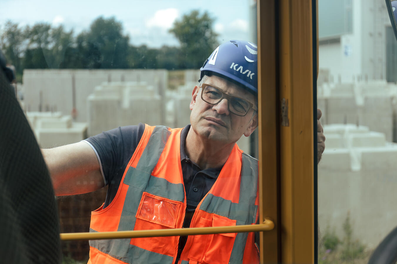 Maschinenführer mit Helm und Warnweste in der Kabine